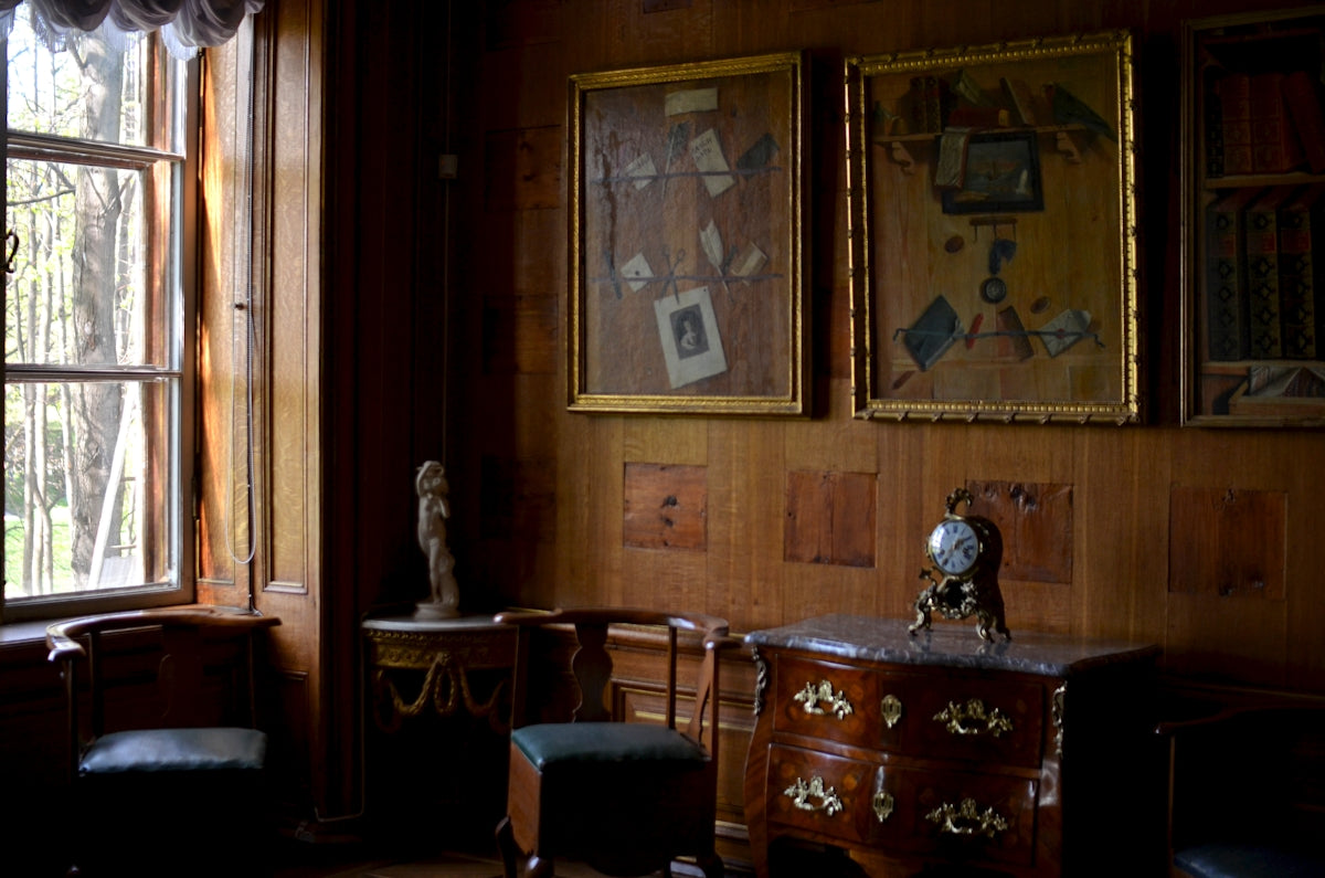 Ornate wooden room with antique furniture and framed pictures.