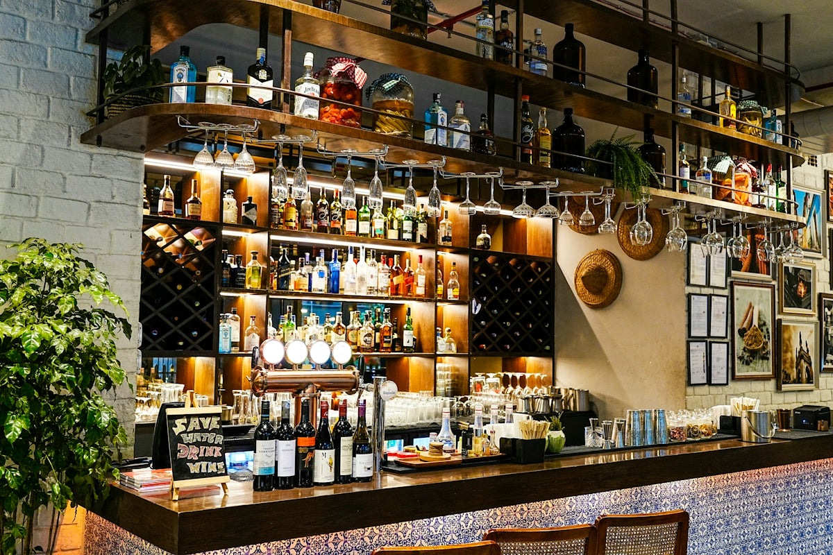 A well-stocked bar with many bottles and hanging glasses.