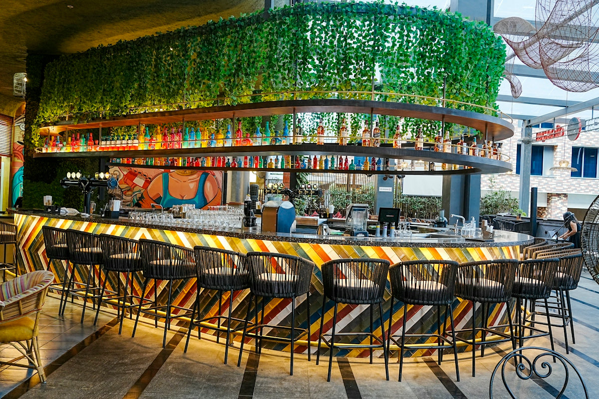 A modern, vibrant bar with colorful lighting and hanging plants.