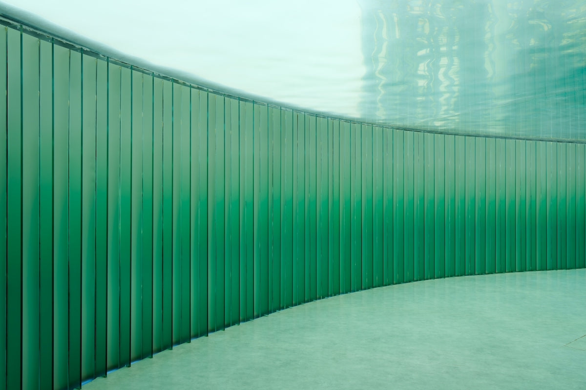 Underwater view of a curved green tiled pool wall.
