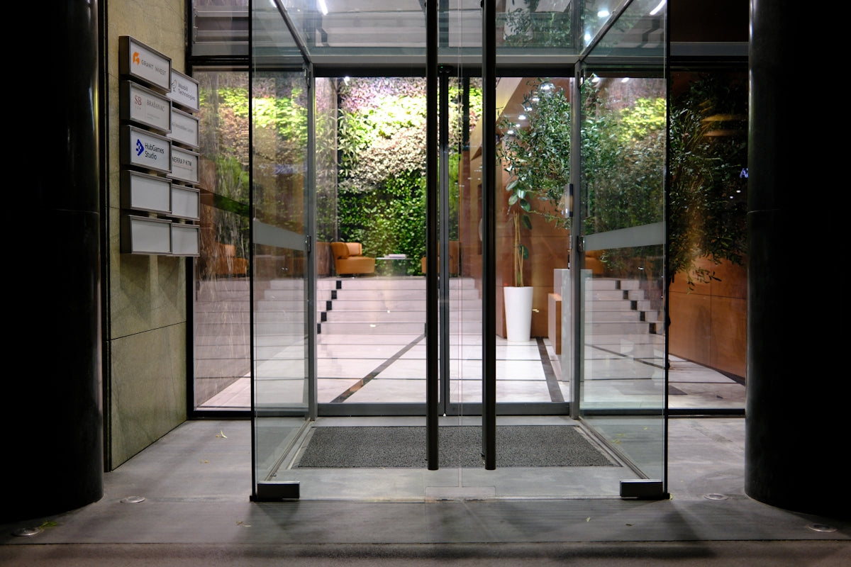 Modern building entrance with glass doors and a green wall.