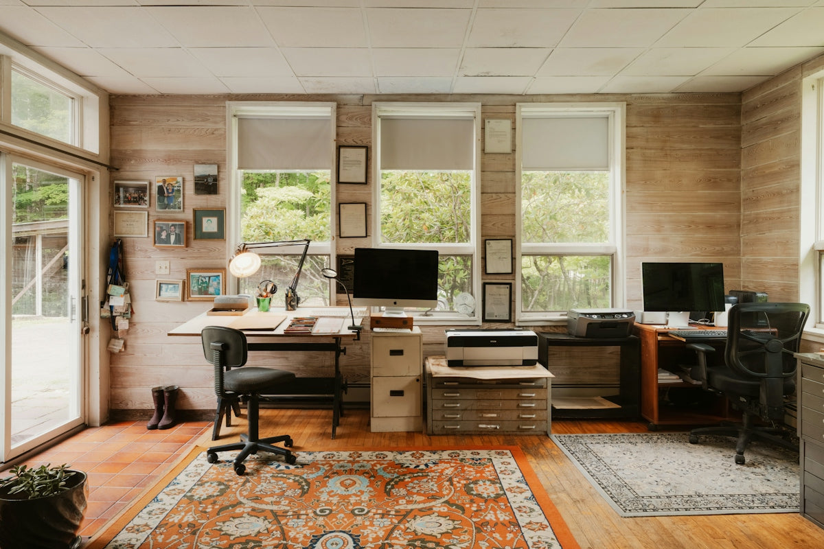 Home office with two desks, computers, and windows