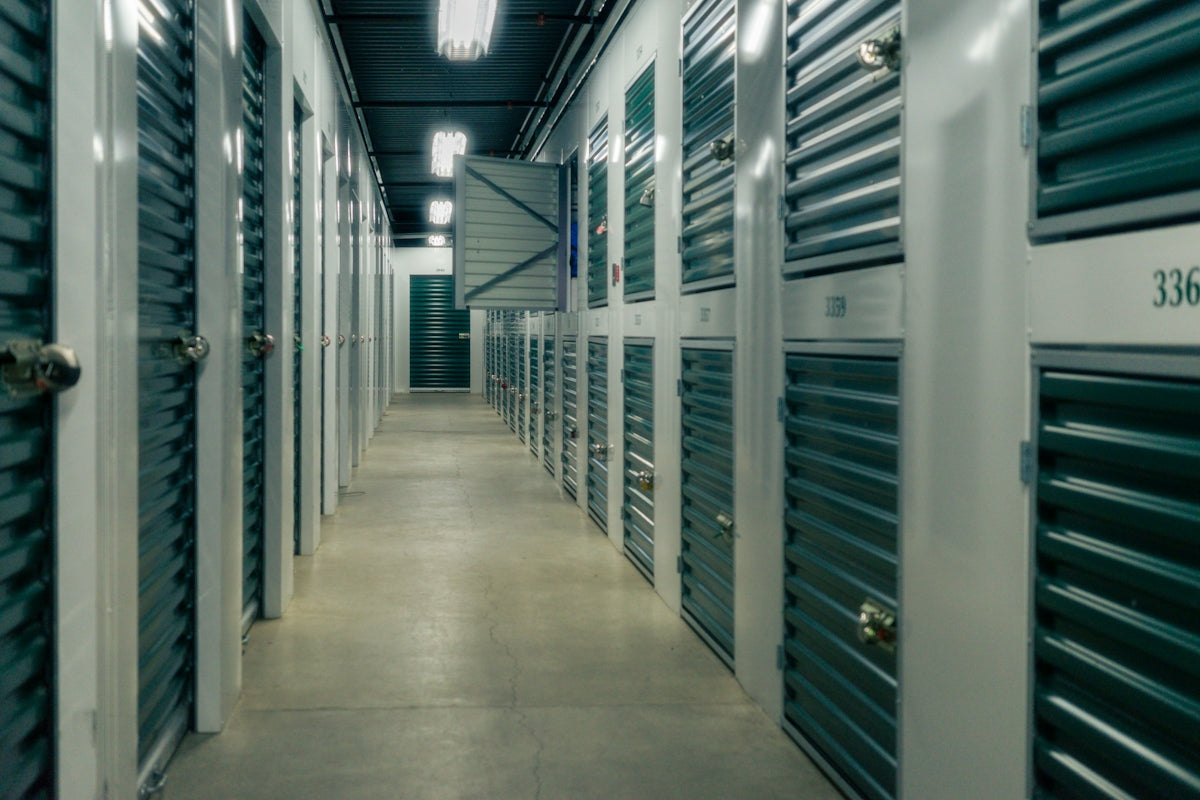 A long hallway lined with green metal storage unit doors and padlocks.
