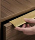 Hand opening a wooden drawer with a gold handle